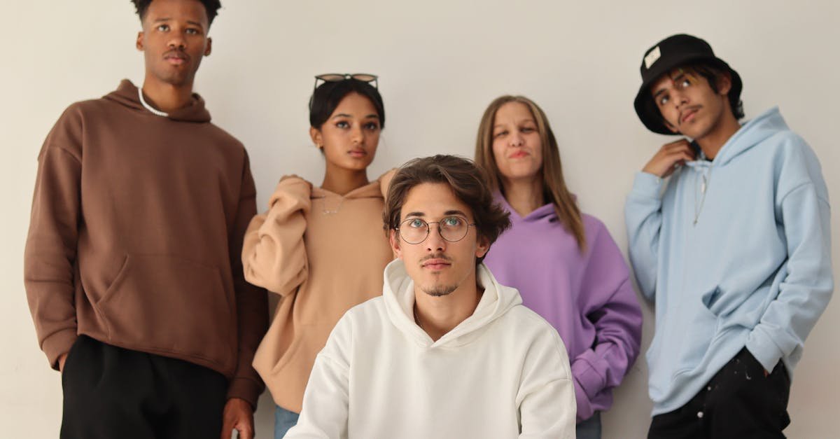 Group of fashionable young adults posing in colorful hoodies in a studio setting.