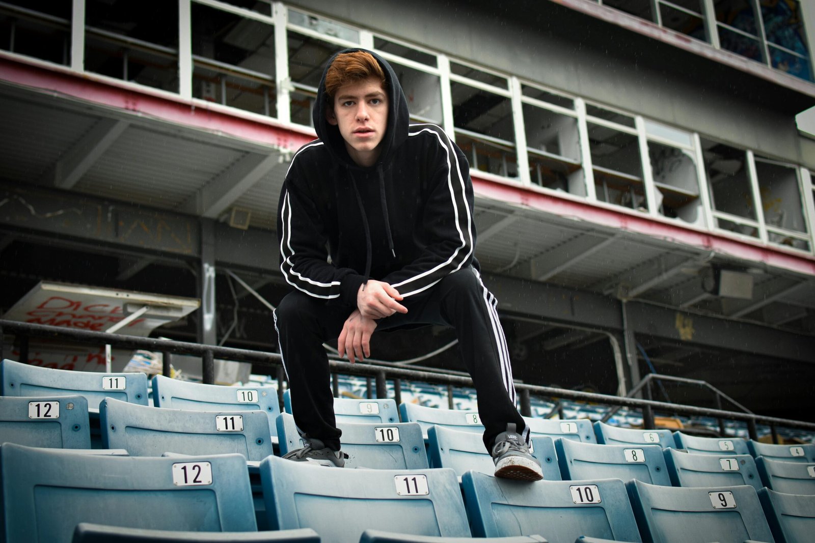 A young man crouches in a hoodie at an empty Nashville stadium.